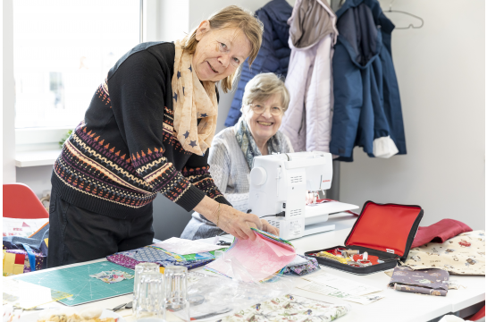 Fotografie: Zwei Seniorinnen arbeiten an einer Nähmaschine.