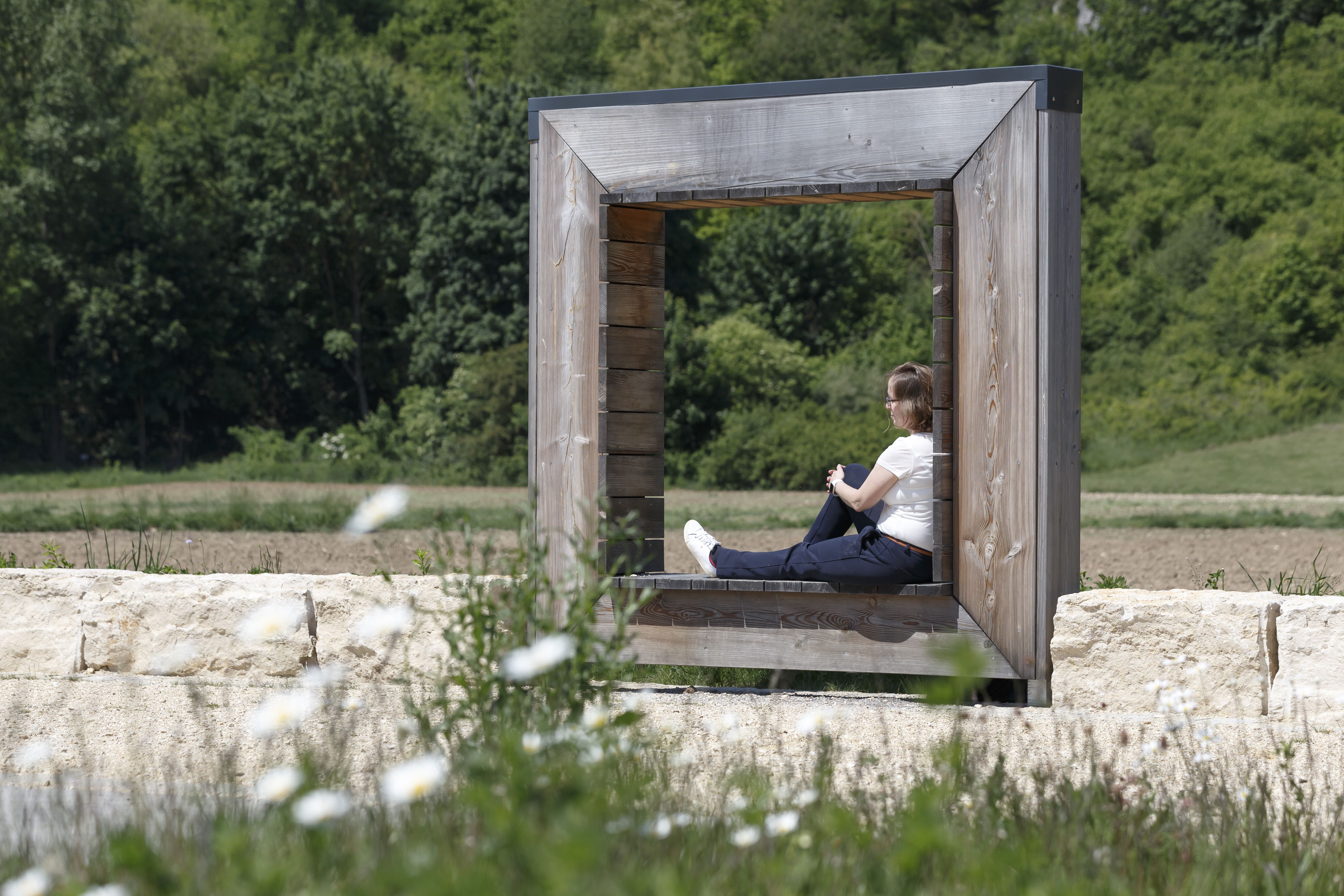 Fotografie: Frau sitzt in hölzernem Kunstwerk im Sandfrauenpark