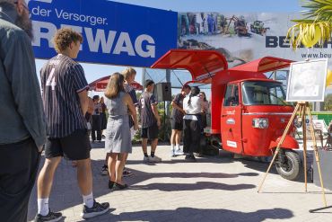 Fotografie: Menschen stehen Schlange vor der roten Eis-Ape.
