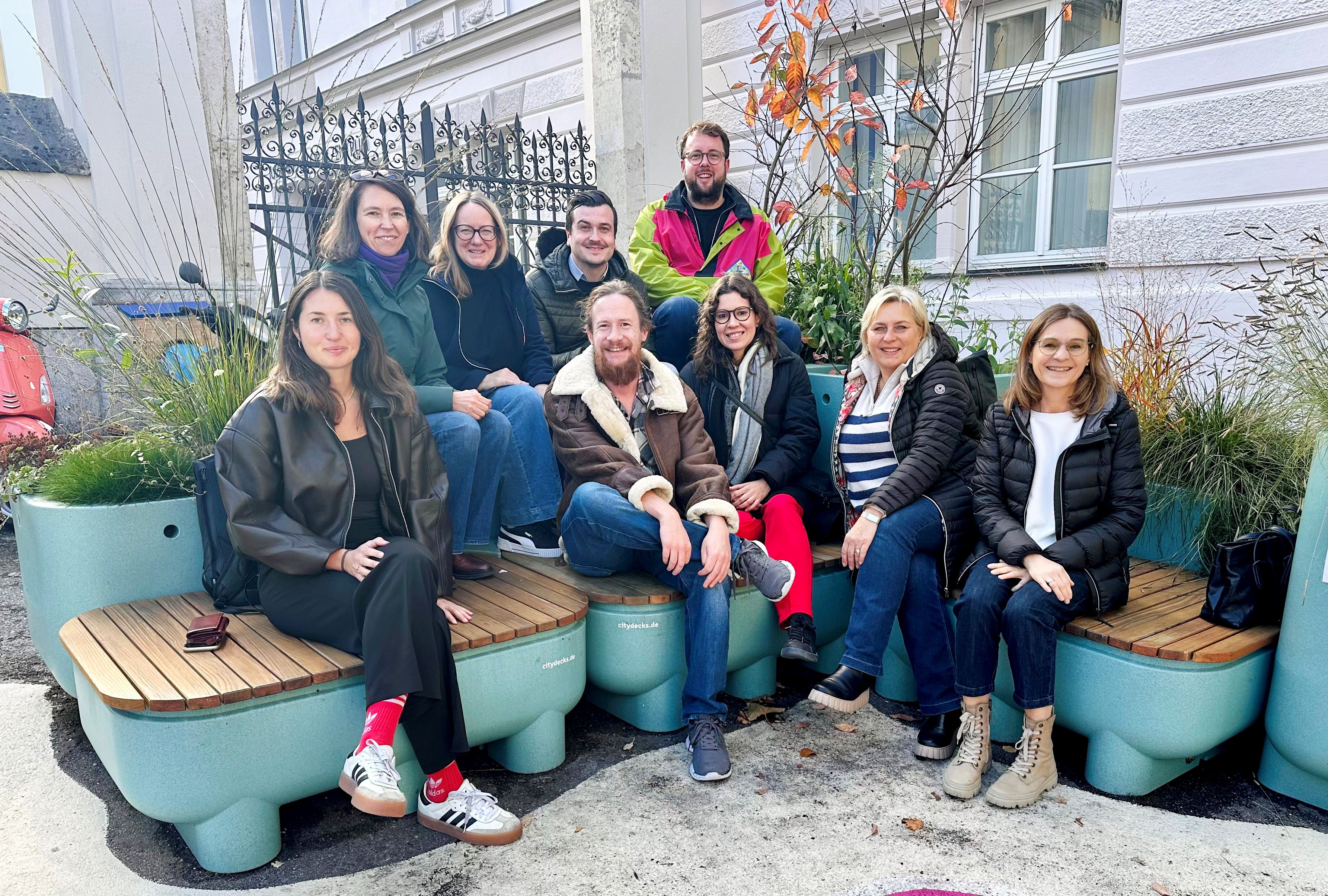 Fotografie: Isabella Costa gemeinsam mit ihrer Abteilung auf dem Obermünsterplatz. Bepflanzte Sitzgelegenheiten, sogenannte CityDecks, sorgen hier seit Mai 2025 für mehr Grün und laden zum Verweilen ein. 