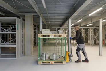 Fotografie: Ein Mann transportiert Steine mit einem Hubwagen im Museumsdepot.
