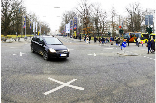 Themenbild Verkehr und Mobilität - Fotografie Auto in einer Kreuzung - rechts im Bild Fußgänger beim Überqueren der Straße und Busse an der Haltestelle