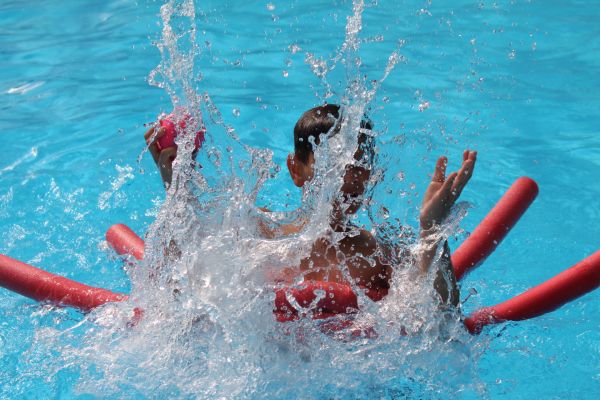 Badespaß auf der Freizeitfahrt. Jugendlicher spritzt mit Wasser im Pool