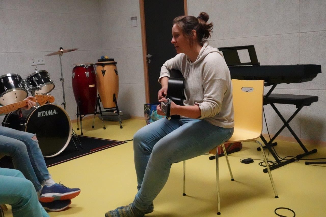 Auf dem Foto ist eine Frau mit einer Gitarre zu sehen.