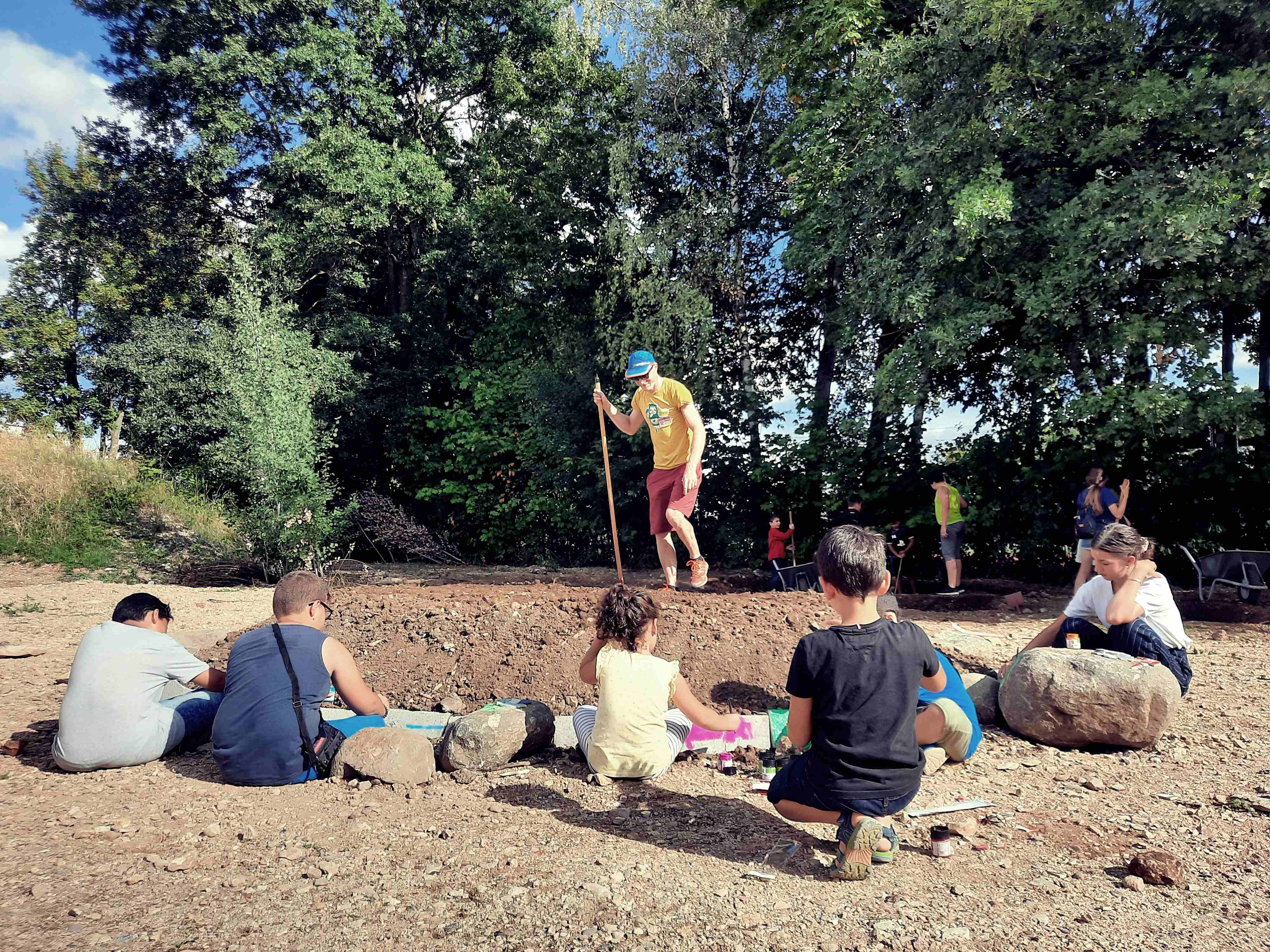 Auf dem Foto sind mehrere Kinder und eine erwachsene Person beim Arbeiten am Rasentier zu sehen. 