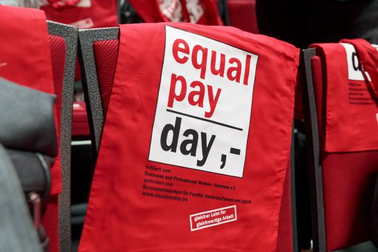 Fotografie: Tasche auf Stuhl mit Aufschrift „equal pay day“
