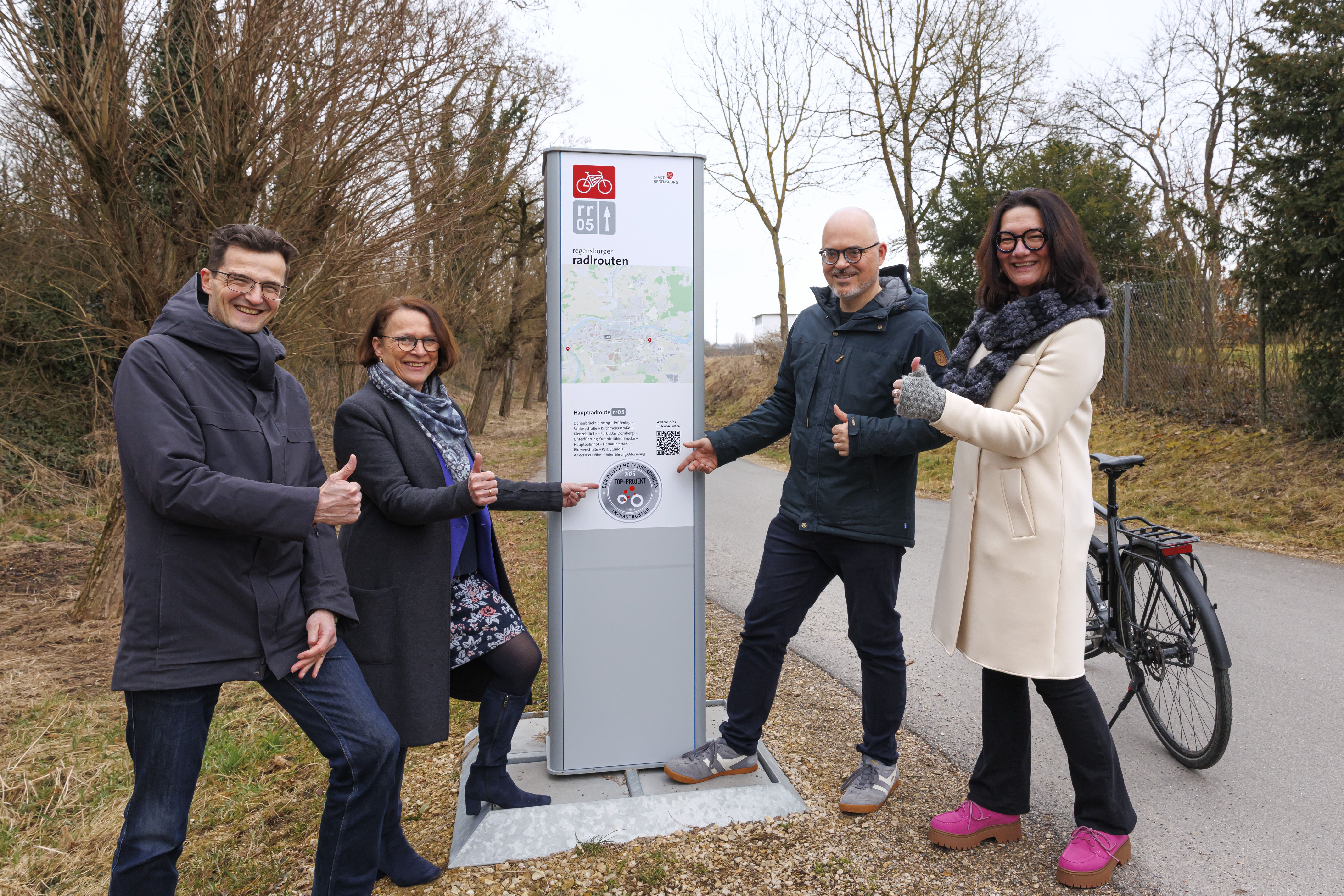 Fotografie – (v. l.) Nahmobilitätskoordinator Thomas Großmüller, Oberbürgermeisterin Gertrud Maltz-Schwarzfischer, Planungs- und Baureferent Florian Plajer und Tanja Flemmig, Leiterin des Stadtplanungsamtes, freuen sich über die TOP 5-Plakette des Deutschen Fahrradpreises. 