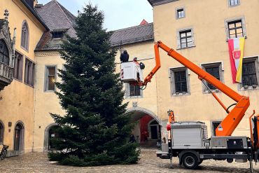 Fotografie: Zwei Männer heben mit einem Hubsteiger den Weihnachtsstern auf den Christbaum am Rathausplatz.