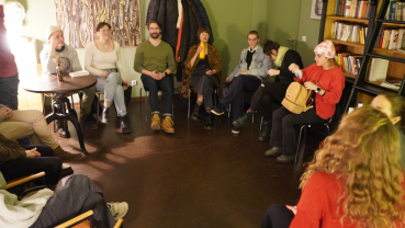Auf dem Foto ist ein Stuhlkreis zu sehen im grünen Salon vom W1. Die Personen sehen entspannt aber konzentriert aus, sie befinden sich mitten in der Gesprächs- und Diskussionsrunde.