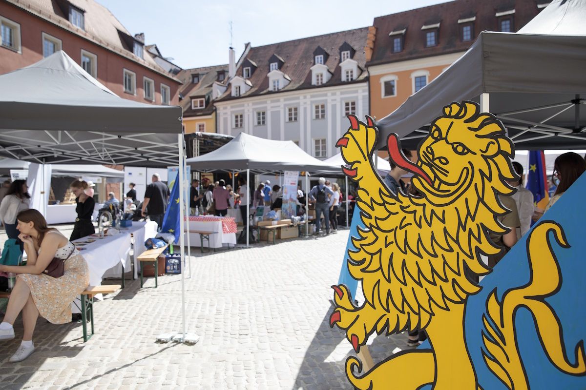 Blick auf den Haidplatz mit vielen Ausstellern. Große Pappfigur in Form eines bayerischen Löwen am rechten Rand des Bildes