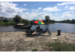 Fotografie - Ein Mann sitzt in einem Liegestuhl unter einem bunten Schirm (C) Bilddokumentation Stadt Regensburg
