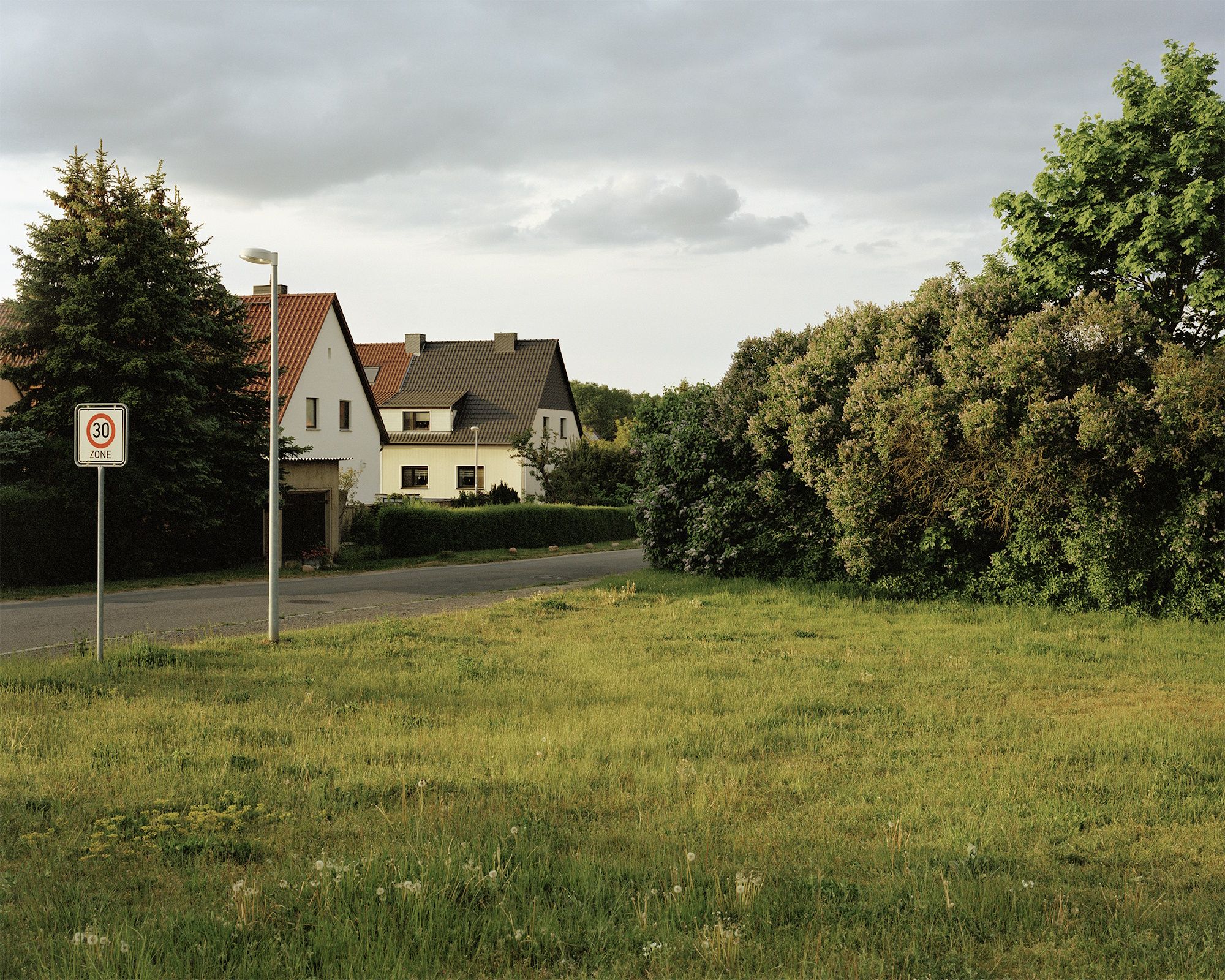Fotografie – Blick über eine Wiese zu zwei ländlichen Häusern