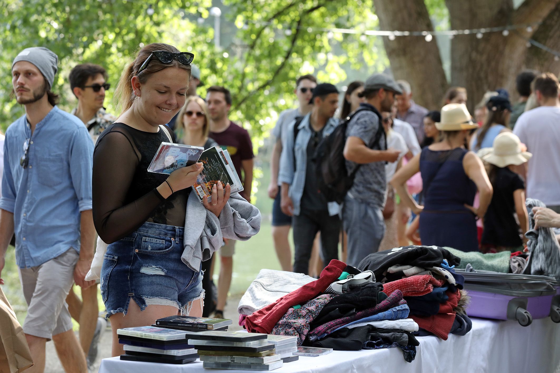 Fotografie: Eine Frau betrachtet an einem Stand Second-Hand-Waren.