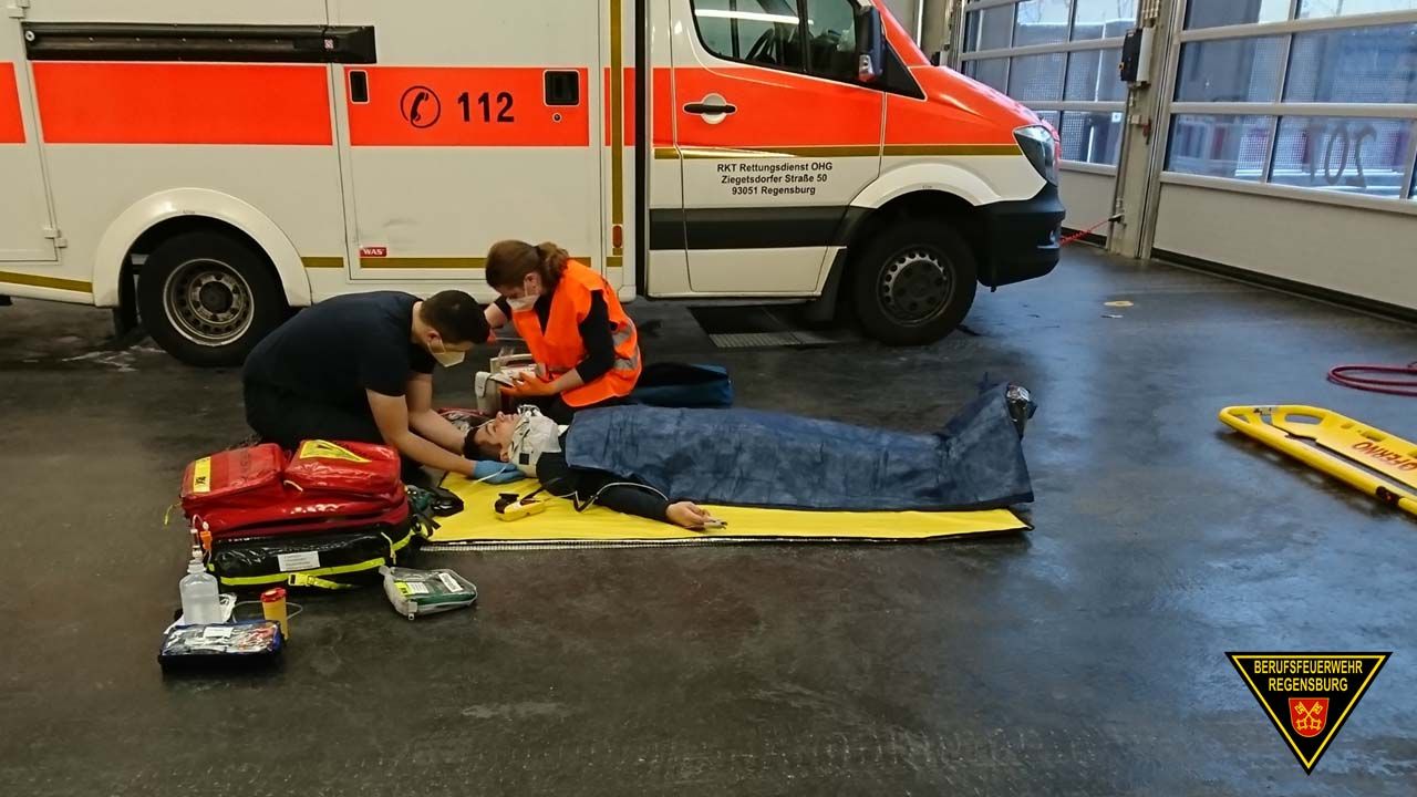 Fotografie: Teilnehmer einer Rettungssanitäter-Abschlussprüfung bei der Versorgung eines am Boden liegenden Patienten.