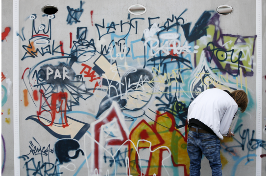 Fotografie: Ein Jugendlicher an einer Graffiti-Wand