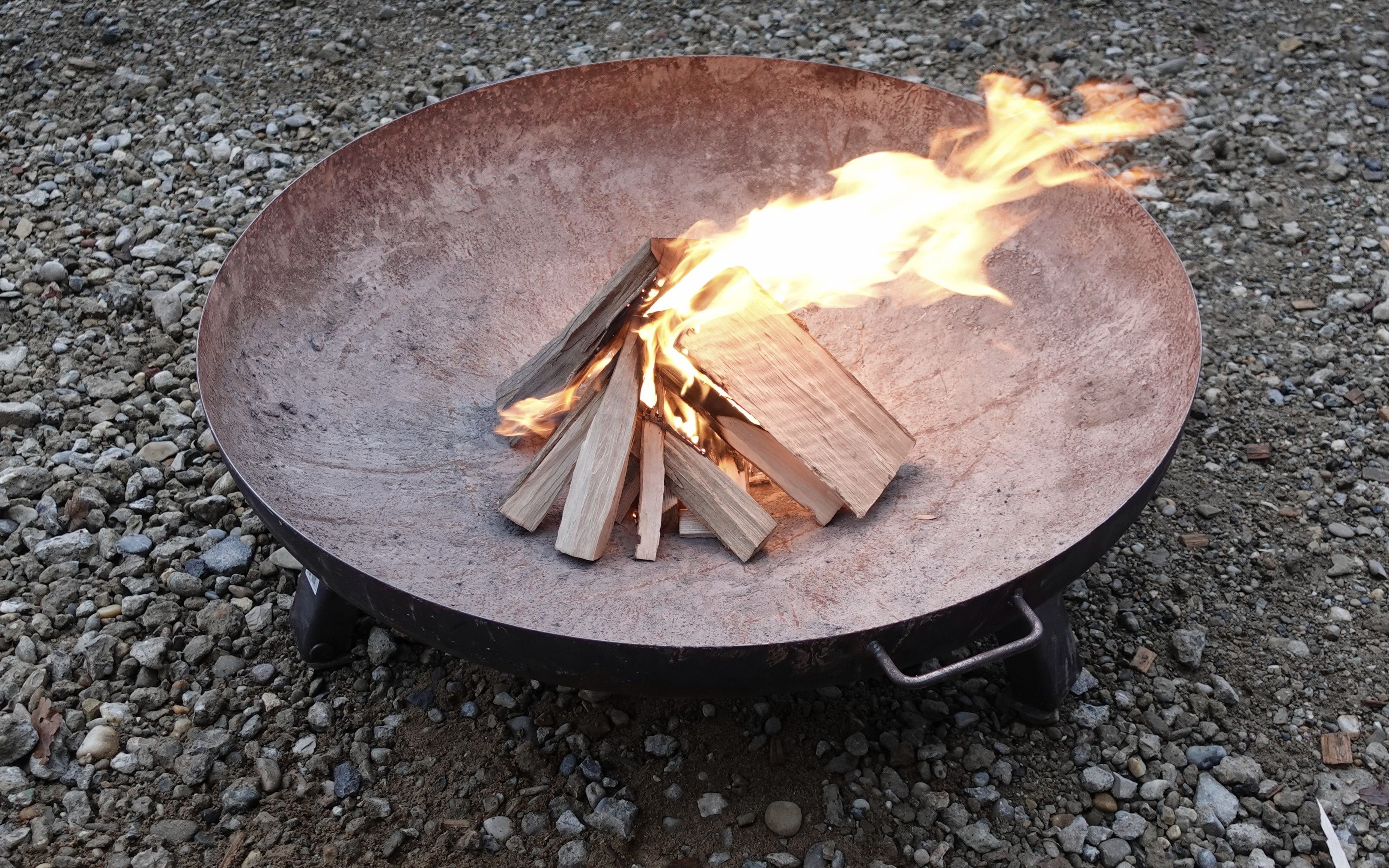 Es ist ein kleines Lagerfeuer in einer Feuerschale zusehen.