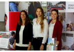 Fotografie – Messestand der Stadt Regensburg mit Vertreterinnen des Personalamts – im Hintergrund eine Messewand mit Fotos von Beschäftigten der Stadt Regensburg (C) Ludwig Elbin, Stadt Regensburg