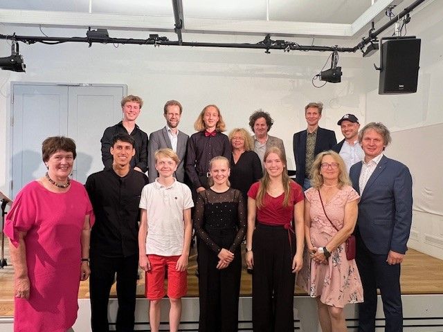 Fotografie – Gruppenfoto aller Preisträgerinnen und Preisträger zusammen mit Stadträtin Bernadette Dechant, Stiftungsleiterin Christiana Schmidbauer, Leiter des Amtes für musische Bildung Ralf Müller, Stadträtin Evelyn Kolbe-Stockert, Stadtrat Alexander Irmisch, Stadtrat Tom Mayr sowie den Botschaftern der Hildegard Schmalzl Musikstiftung Tom Woods und Michael Wolf
