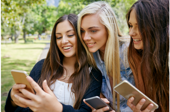 Fotografie: Drei junge Frauen schauen in ein Smartphone.