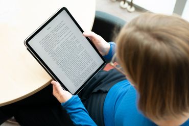 Fotografie - Eine Person liest ein Buch auf einem Tablet.