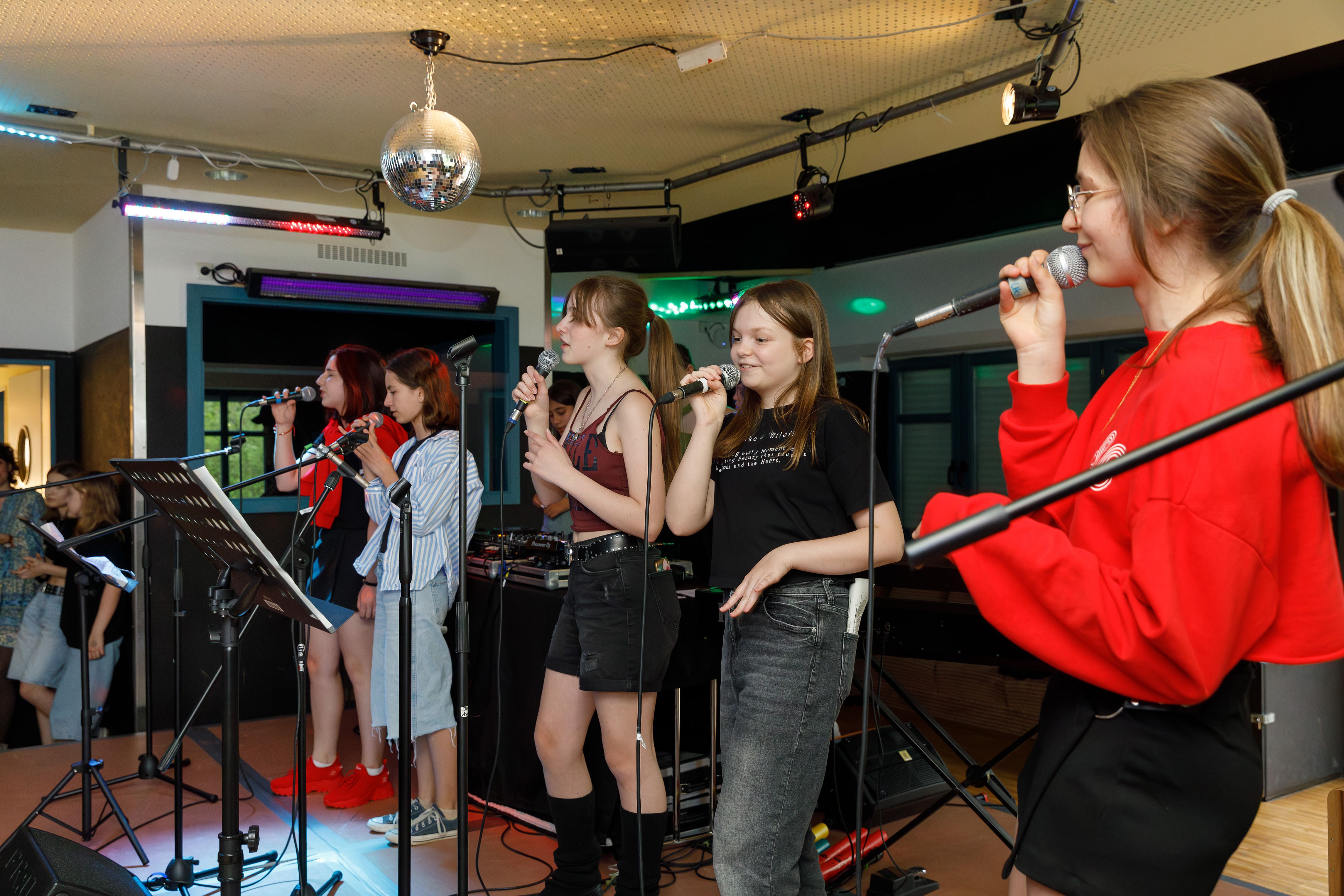 Fünf Mädchen vom Gesangsworkshop stehen beim Abschlusskonzert auf der Bühne und singen. 