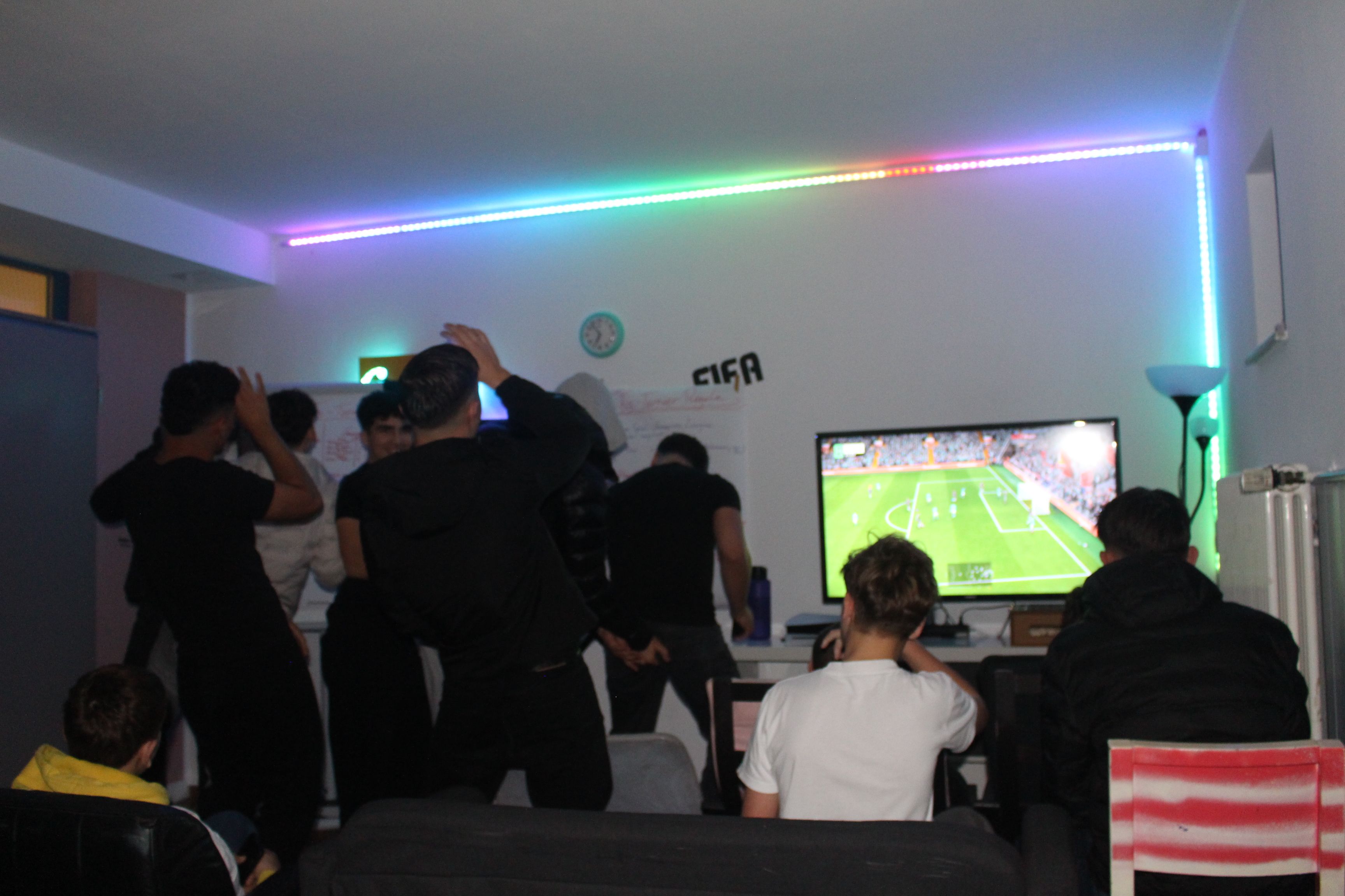 Jubelnde Jugendliche beim FIFA Turnier. im Hintergrund sieht man ein Fußballfeld auf dem Fernseher