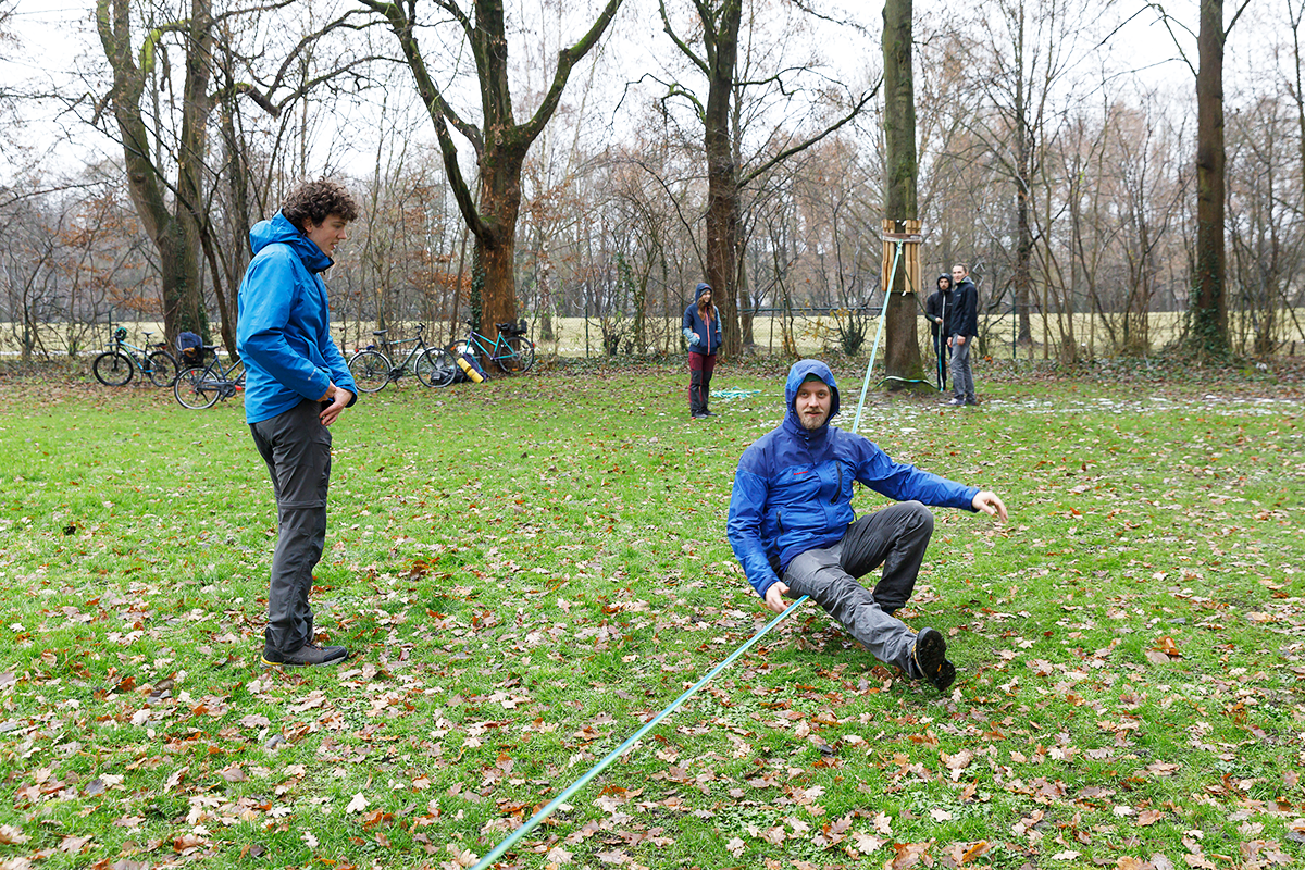 Mann sitzt auf gespannter Slackline