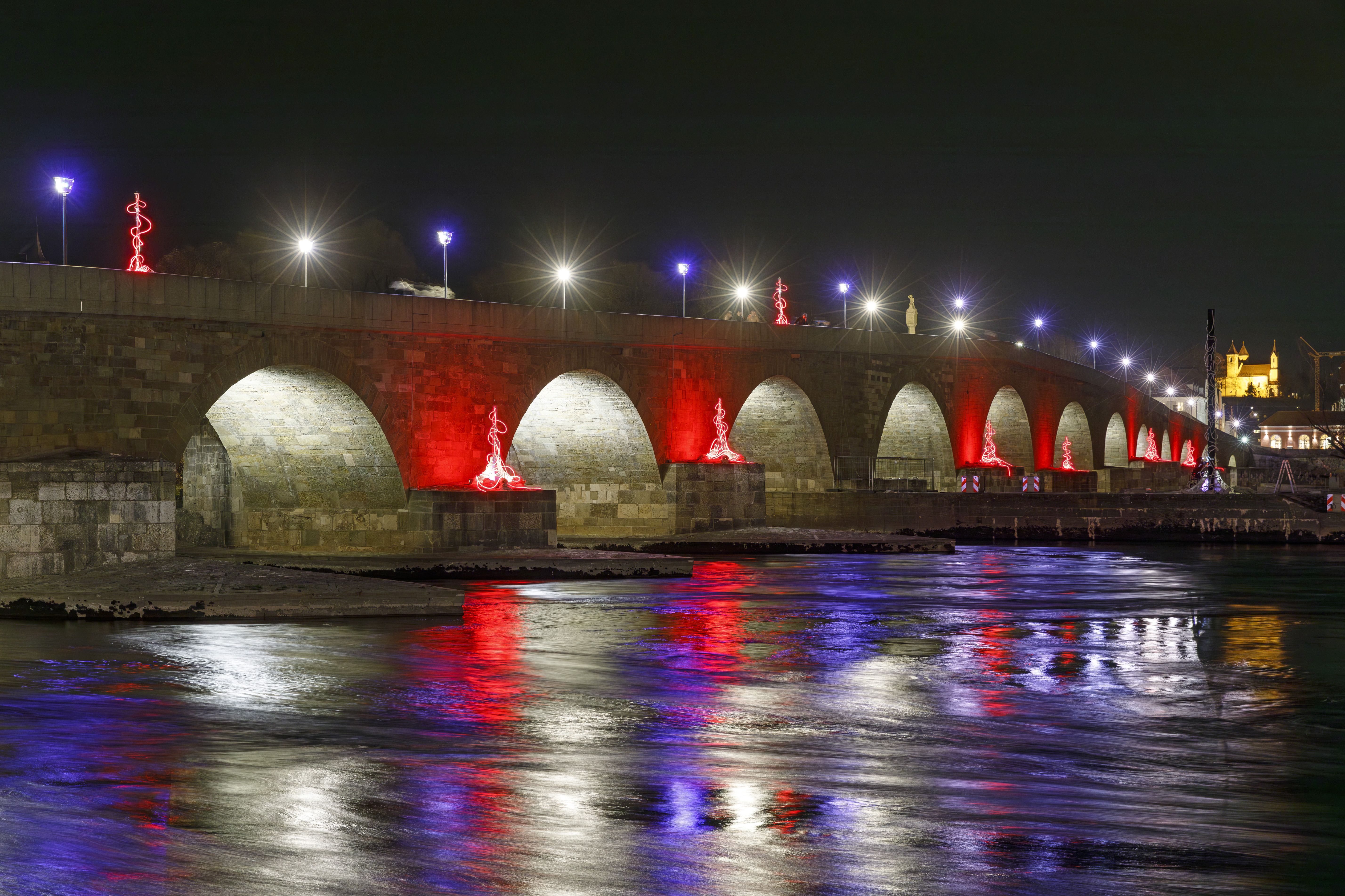 Die Steinerne Brücke wird durch das RE.LIGHT Festival in verschiedenen Farben beleuchtet.