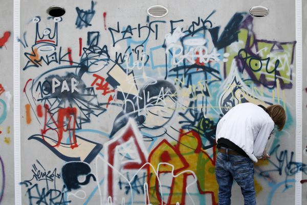 Fotografie: Ein Jugendlicher an einer Graffiti-Wand