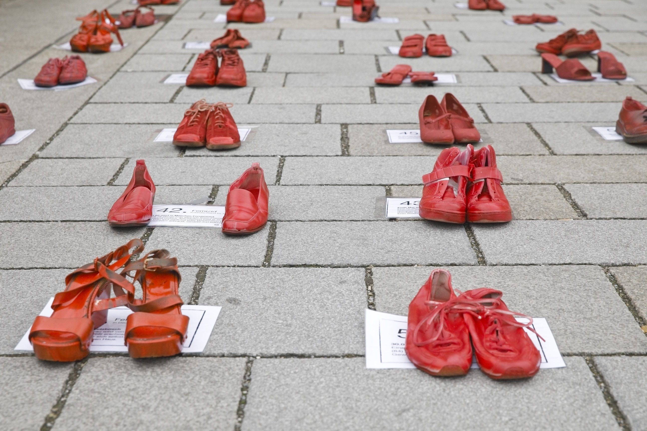 Fotografie: Rote Schuhe stehen in Reihen auf der Steinernen Brücke.