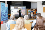 Fotografie - Internationale Jugendkonferenz 2022 - im Vordergrund Publikum, im Hintergrund auf der Bühne Jugendliche bei der Präsentation der Städte (C) Bilddokumentation Stadt Regensburg