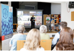 Fotografie - Internationale Jugendkonferenz 2022 - im Vordergrund Publikum, im Hintergrund auf der Bühne Jugendliche bei der Präsentation der Städte