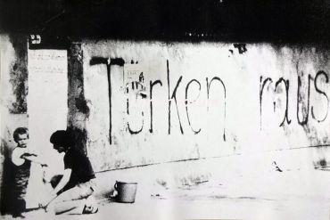 Fotografie - : Eine Frau übermalt mit ihrem kleinen Sohn den an eine Hauswand geschriebenen Schriftzug „Türken raus“