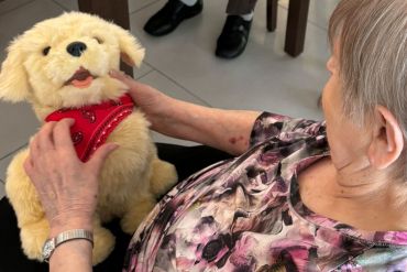 Fotografie: Eine Dame hält einen Stoffhund-Roboter in den Händen.