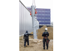 Fotografie - Montage des Funkmastes am Schlauchturm - zwei Mitarbeiter überwachen das Anheben eines Teils des Funkmastes 