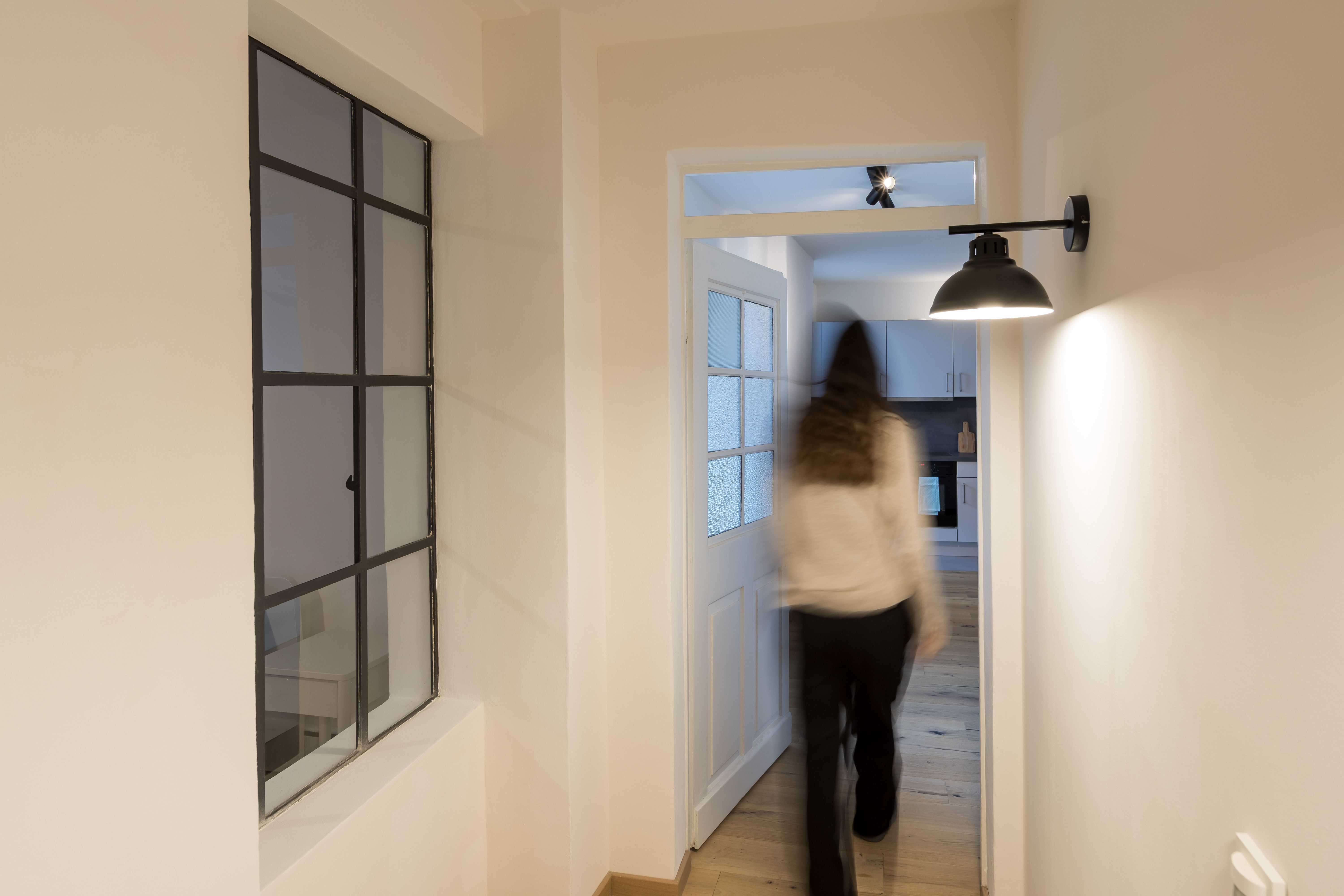 Fotografie - Atelierwohnung 1 - Zu sehen ist eine verschwommene weibliche Silhouette, die vom Gang in die Küche läuft.