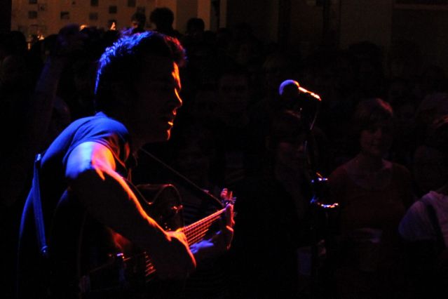 Konzert der Band "Polite Sleeper" im W1 - Zentrum für junge Kultur. Blick von der Bühne ins Publikum, im Vordergrund der Sänger und Gitarrist der Band im Scheinwerferlicht.