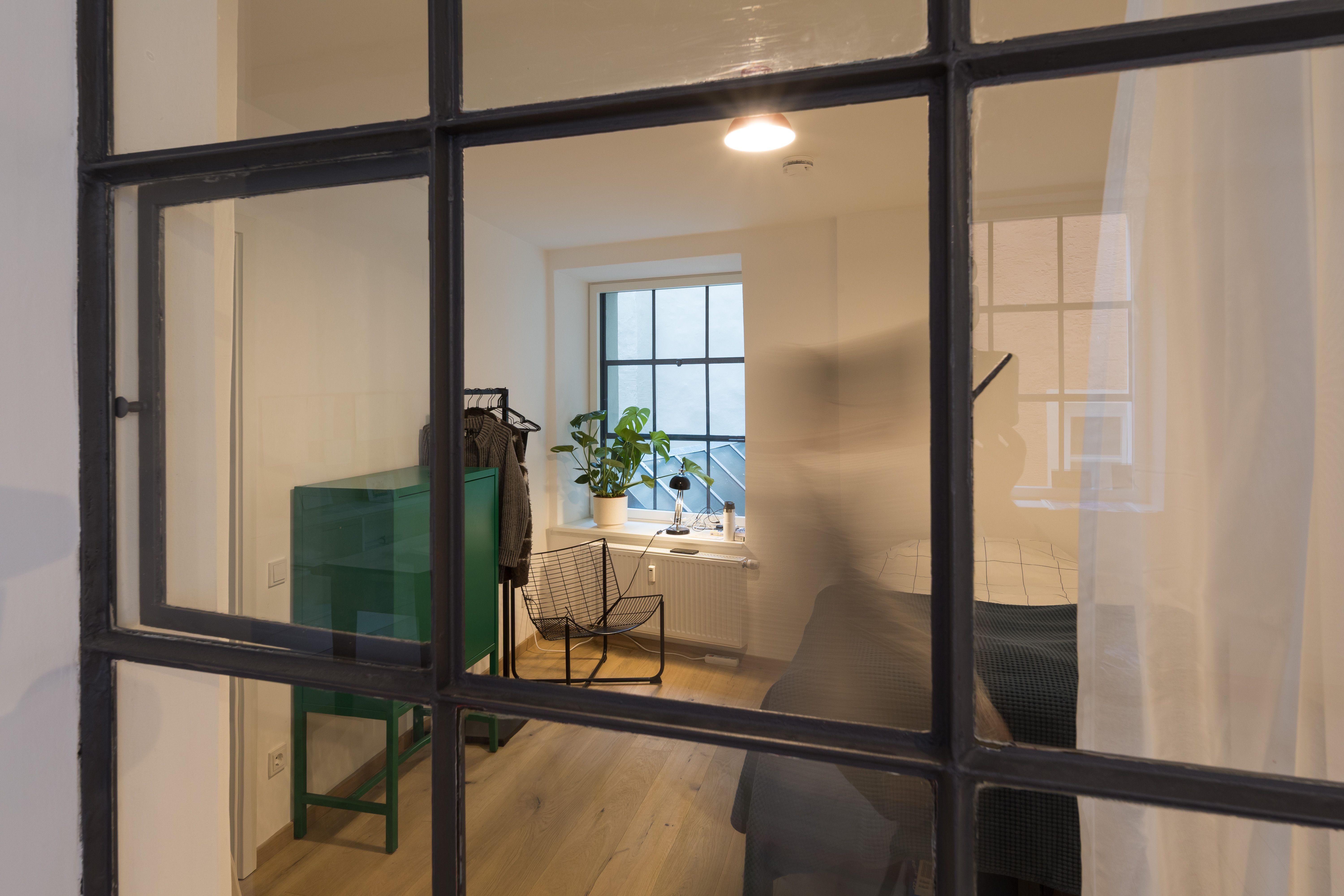 Fotografie - Atelierwohnung 2 - Zu sehen ist eine verschwommene männliche Silhouette, die durch das Schlafzimmer läuft.