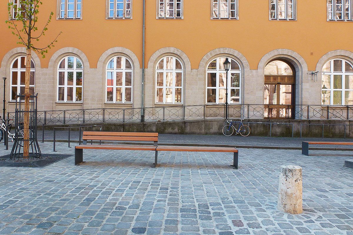 Fotografie - Holzbank vor gelbem Gebäude
