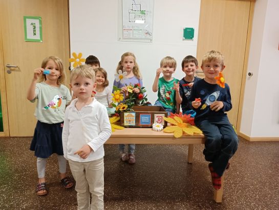 Lachende Kinder stehen mit den gezogenen Losen um einen Tisch.