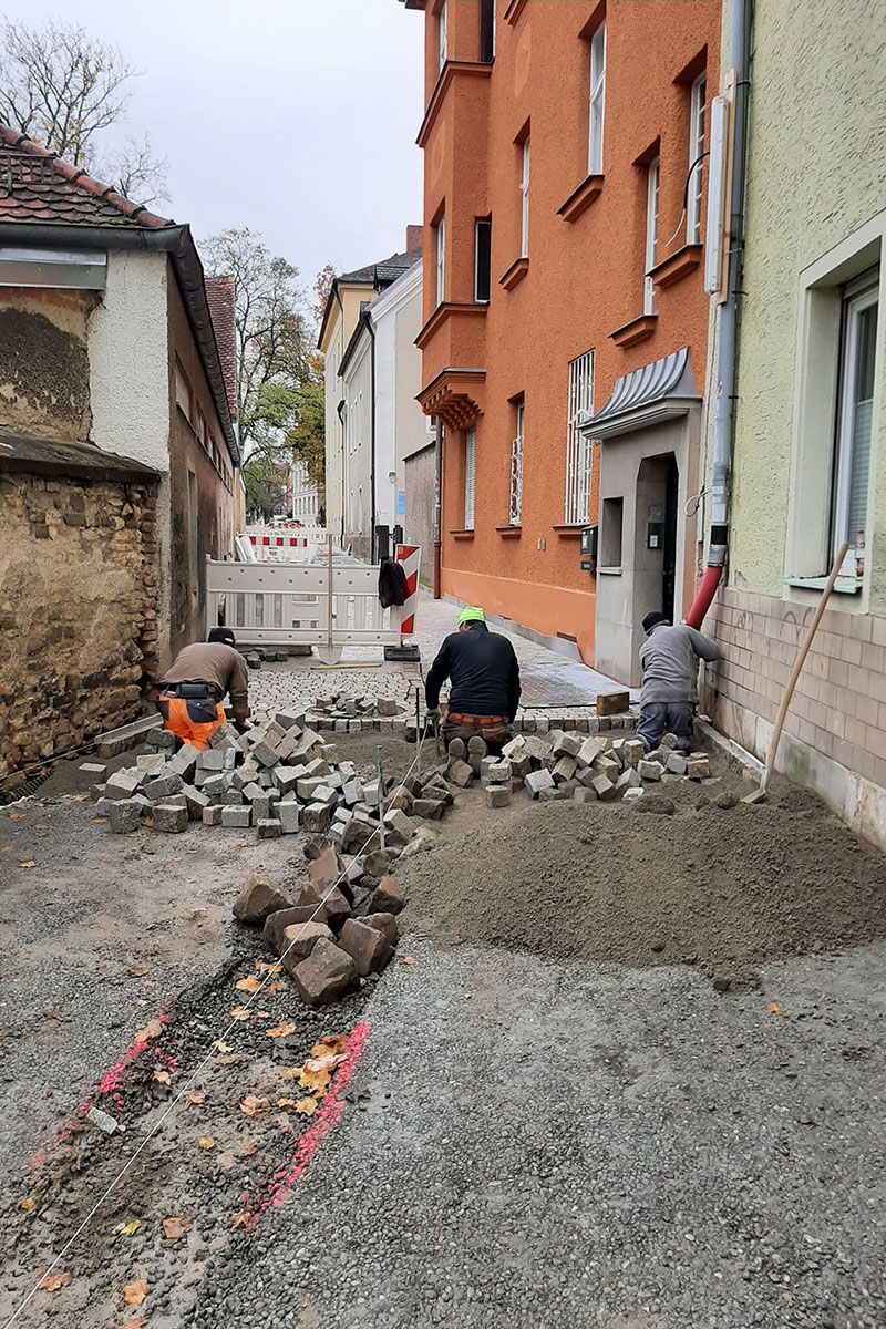 Fotografie - Verlegung des warmtonigen Granit Kleinstein- und Binderpflaster, Verlegung der 2-zeiligen Hirschlinger Rinne 