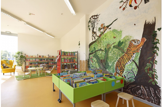 Container und Buchregale mit Kinderbüchern, Wandgemälde Dschungel
