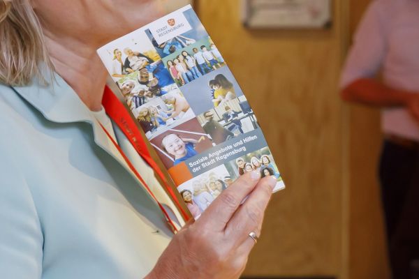 Fotografie: Eine Frau hält eine Broschüre „Soziale Angebote und Hilfen der Stadt Regensburg“.