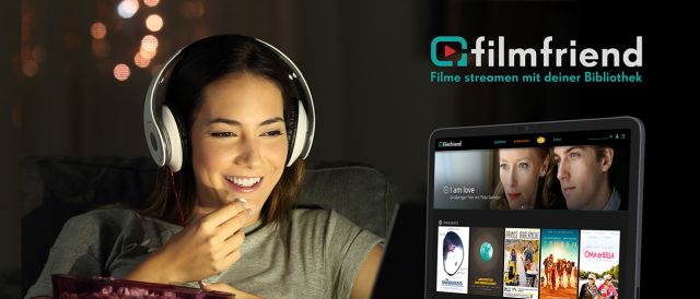 Eine Frau sitzt mit Kopfhörern und Popcorn vor einem Laptop 