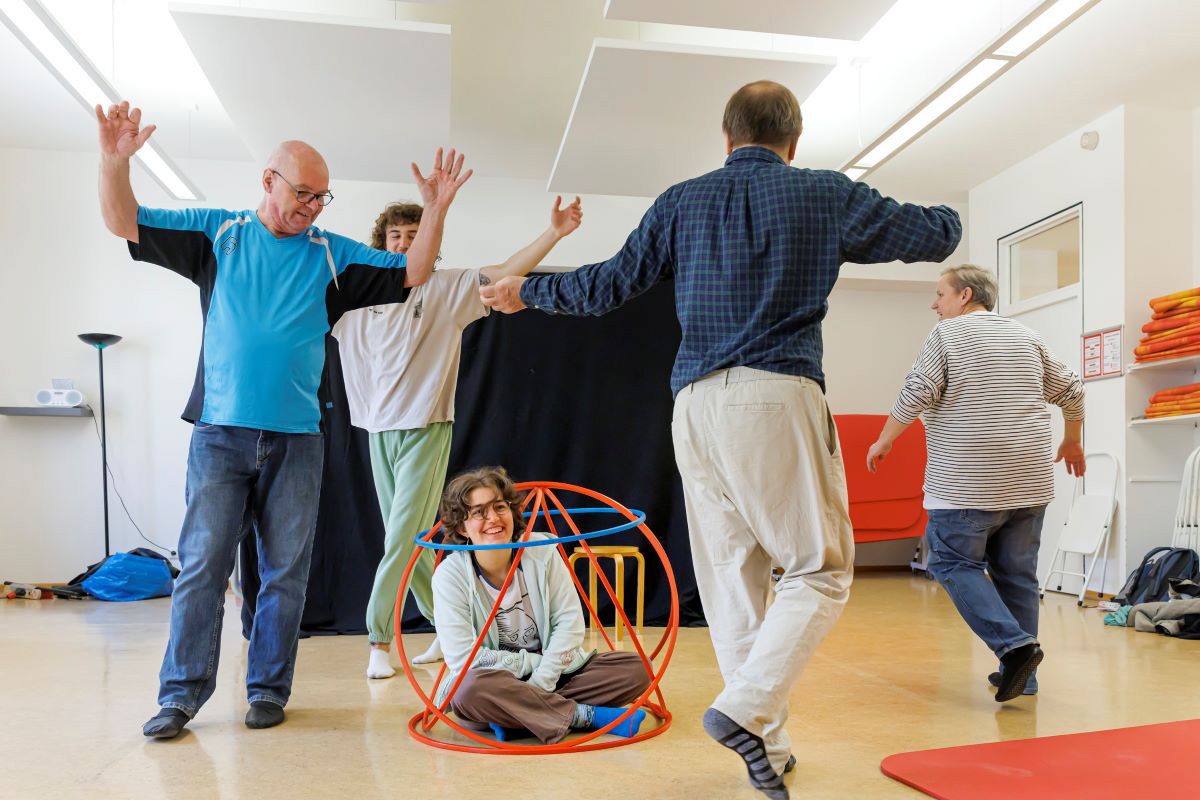 Fotografie: Szene, Teilnehmer laufen um Person am Boden in einem „Käfig“