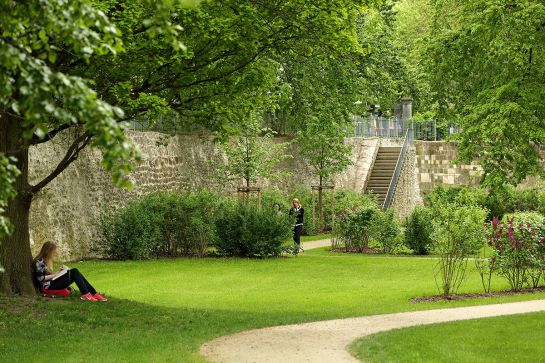 Fotografie - ehemaliger Stadtgraben, Frau sitzt auf Wiese und liest