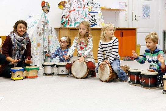 Themenbild Familien - Kinderbetreuung - Fotografie - Kinder und eine Betreuerin mit Trommeln