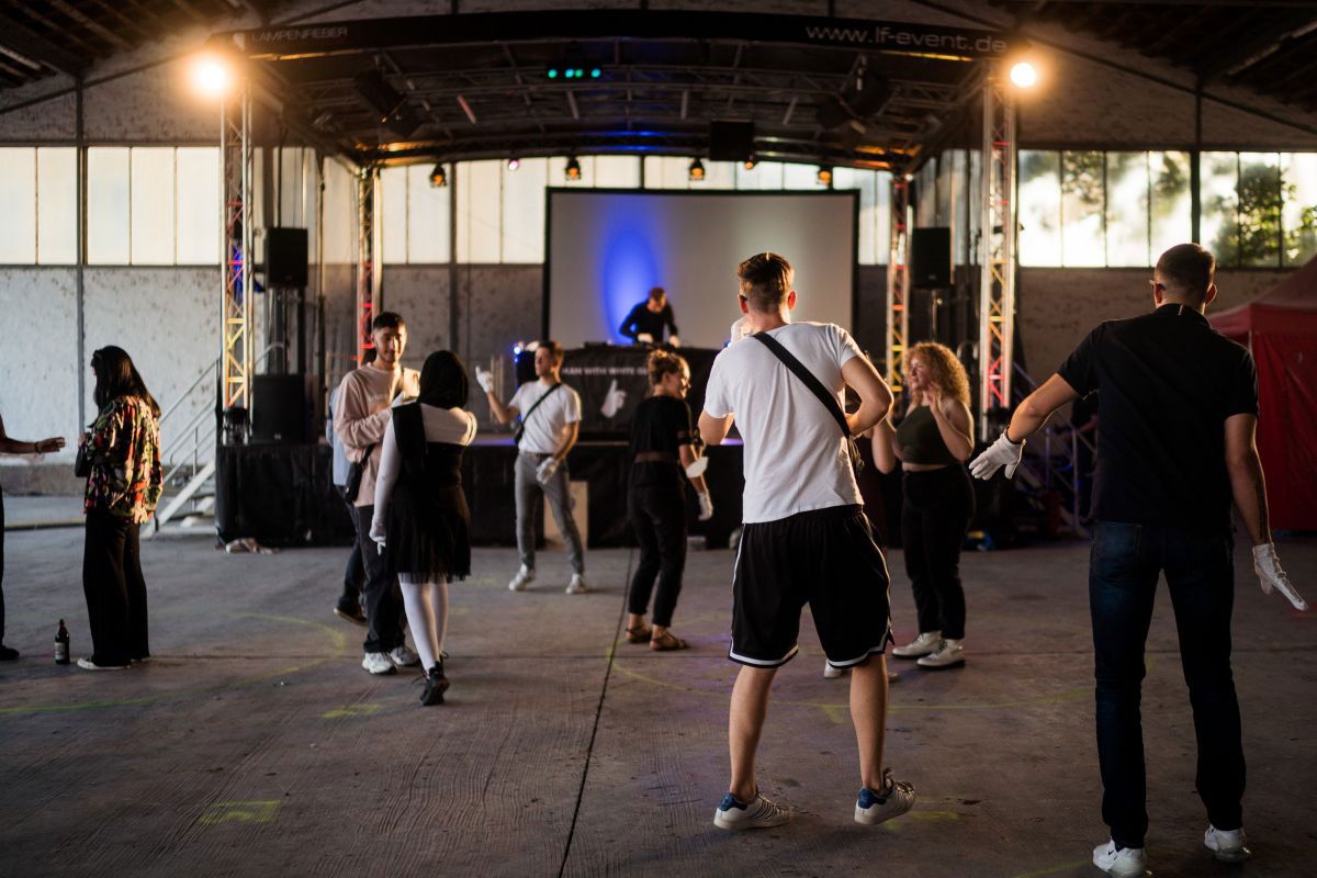 Fotografie – Tanzende Personen, im Hintergrund ein DJ