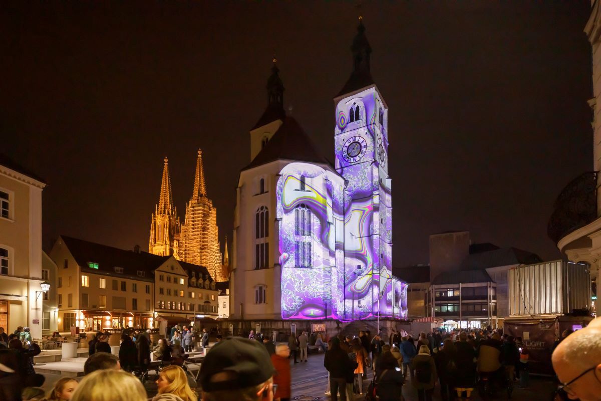 Fotografie: Neupfarrkirche beim RE.LIGHT Festival 2024 in weißt und lila beleuchtet, im Hintergrund der Dom