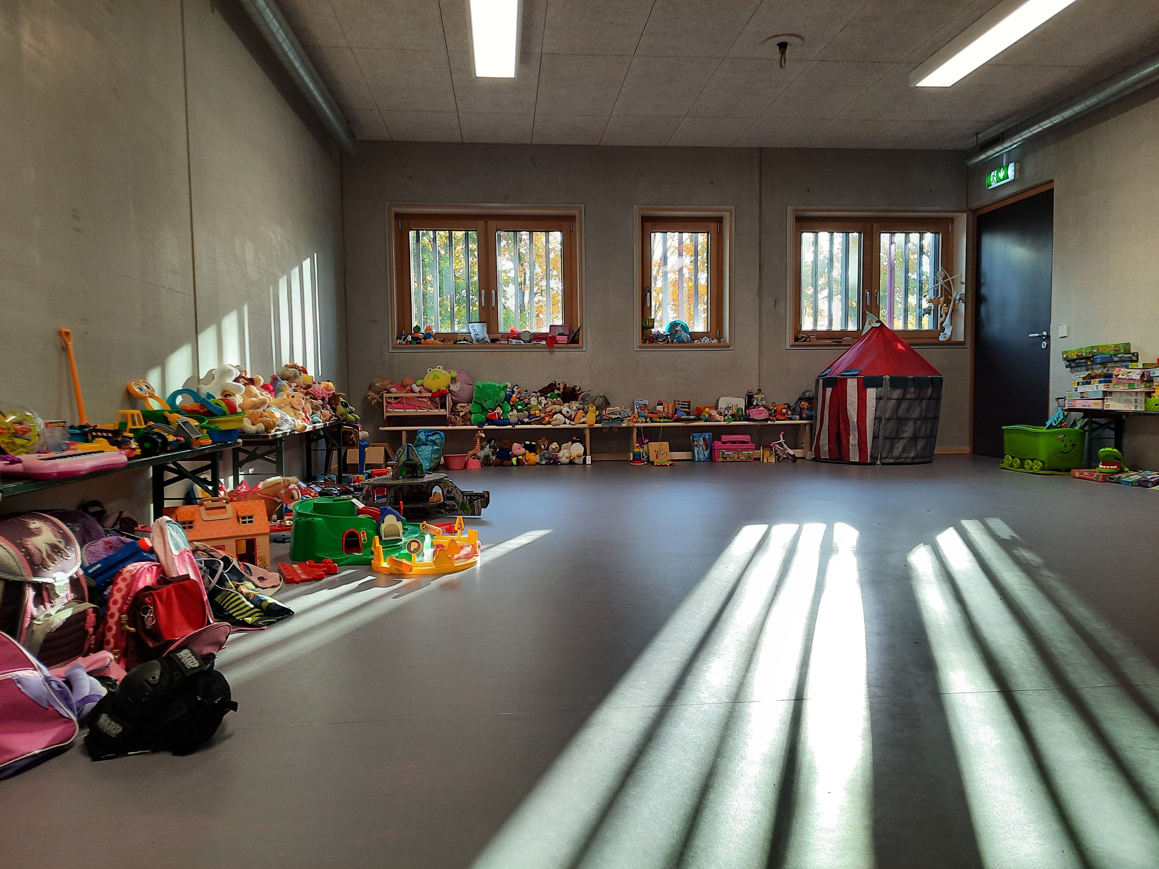 Fotografie - Raum mit vielen bunten Spielsachen entlang der Wände aufgestapelt